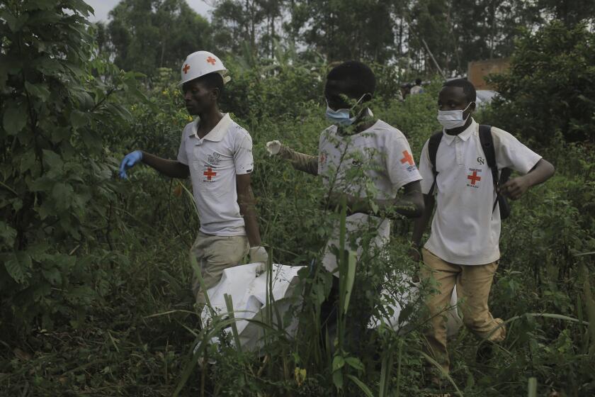 Red Cross volunteers carry the body of a civilian, who was killed in the Democratic Republic of Congo North Kivu province village of Mukondi, Thursday March 9, 2023. At least 36 were killed when the Allied Democratic Forces, a group with links to the Islamic State group, attacked the village and burned residents' huts. (AP Photo/Socrate Mumbere)