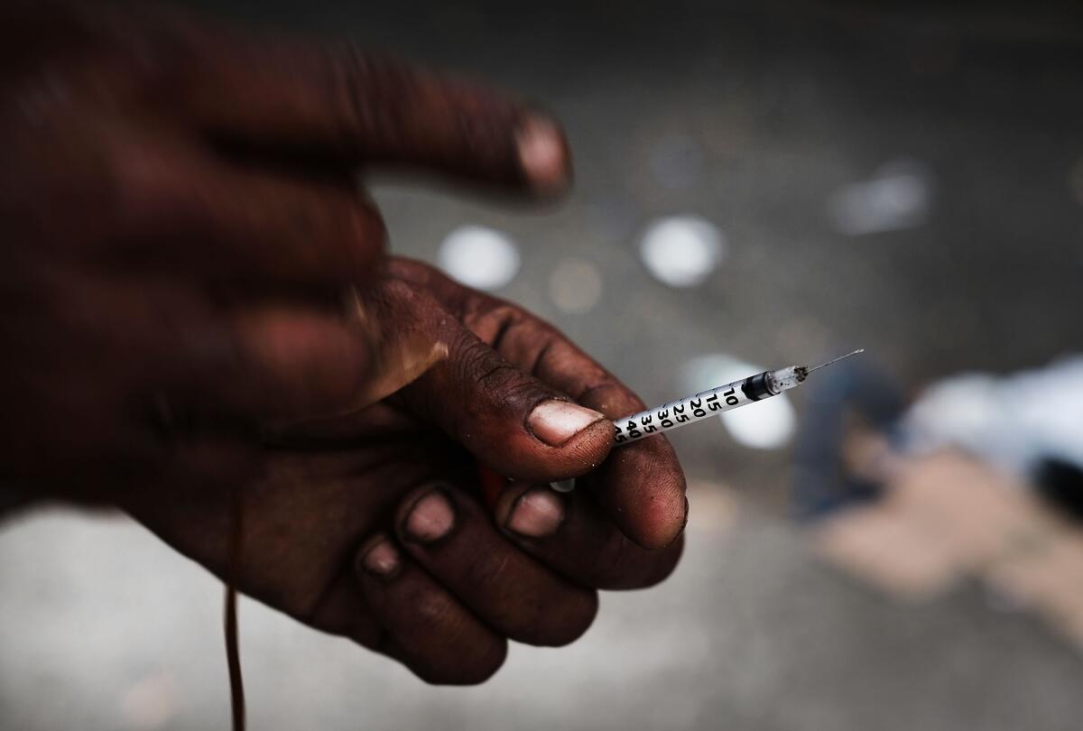 A heroin user displays a needle 