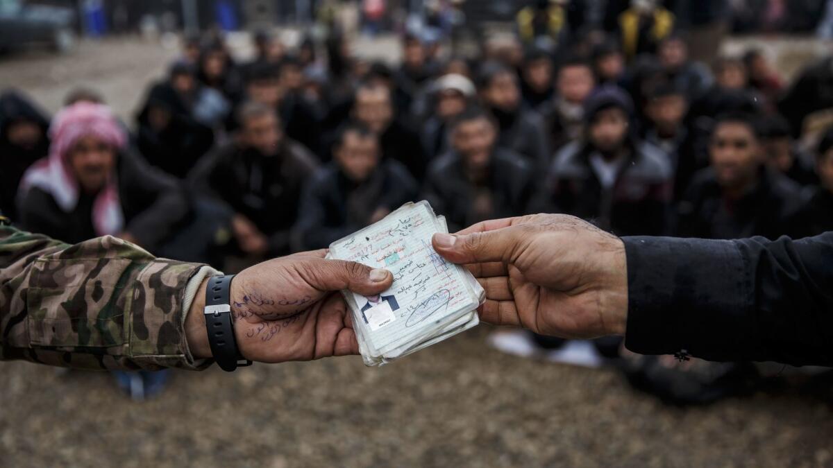 Identification papers of displaced people are checked against a database of Islamic State members at a camp in Hamam Alil on March 23, 2017.