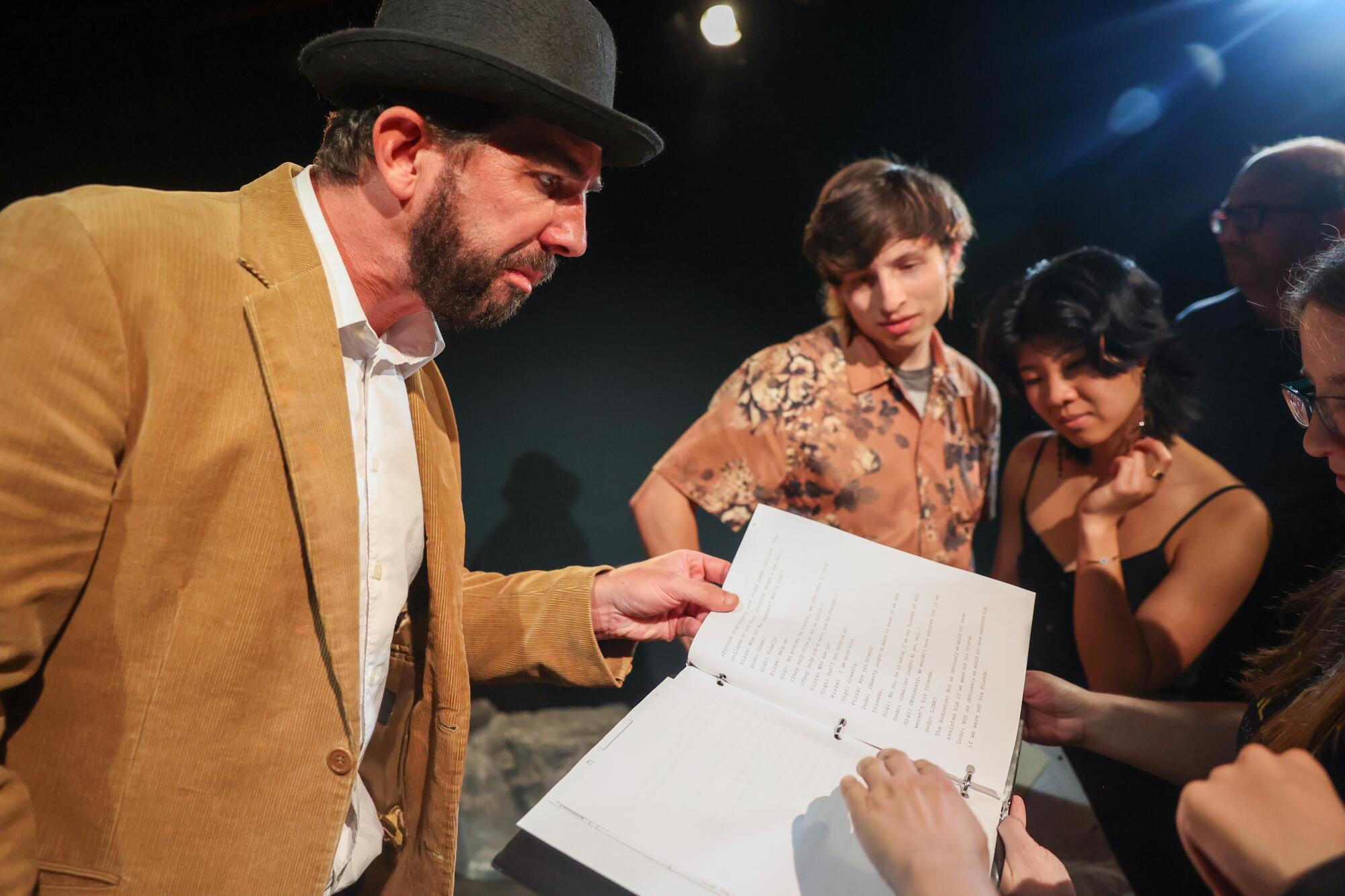 Actor Justin Okin looks through the stage play script for lines to give audience members context for the next clue.