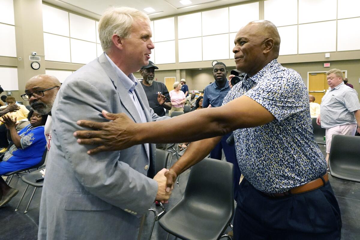 A white man and a Black man shaking hands at a campaign meet-and-greet 