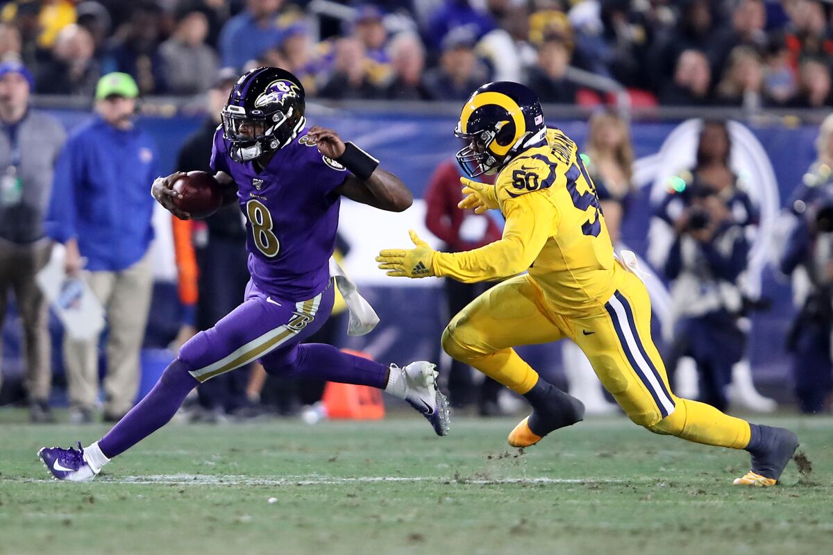 Baltimore Ravens quarterback Lamar Jackson is chased by Rams linebacker Samson Ebukam.