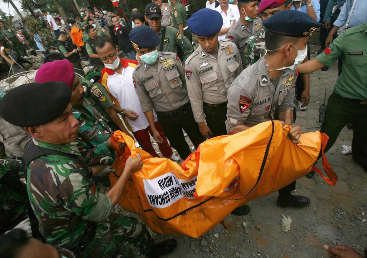 Personal militar carga con una bolsa para cadáveres que contiene los restos de una víctima del accidente, luego de que un avión militar de transporte se estrelló en Medan, en el norte de la isla de Sumatra, Indonesia, el 30 de junio de 2015. (Foto AP /Binsar Bakkara)