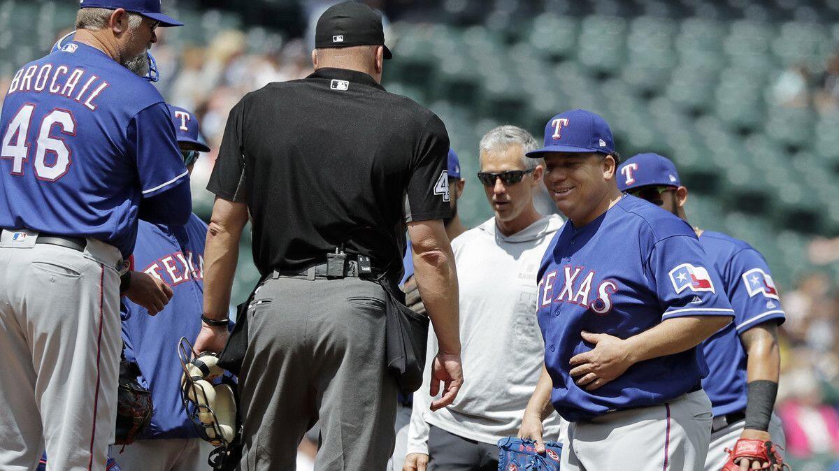 Texas Rangers pitcher Bartolo Colon, right, rubs his stomach and returns to the mound after being hit by a ball.