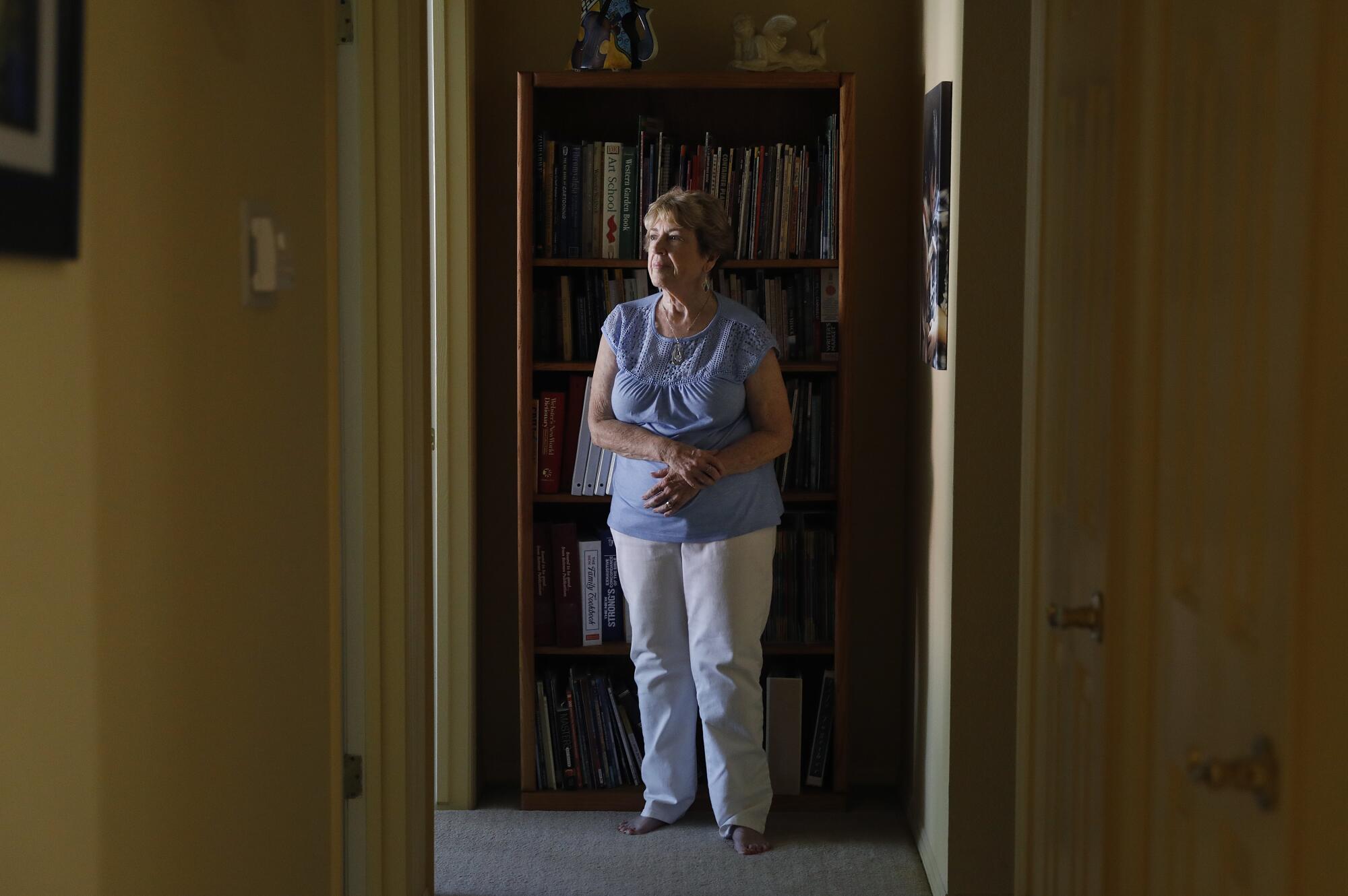 A woman stands in a hallway at her home.