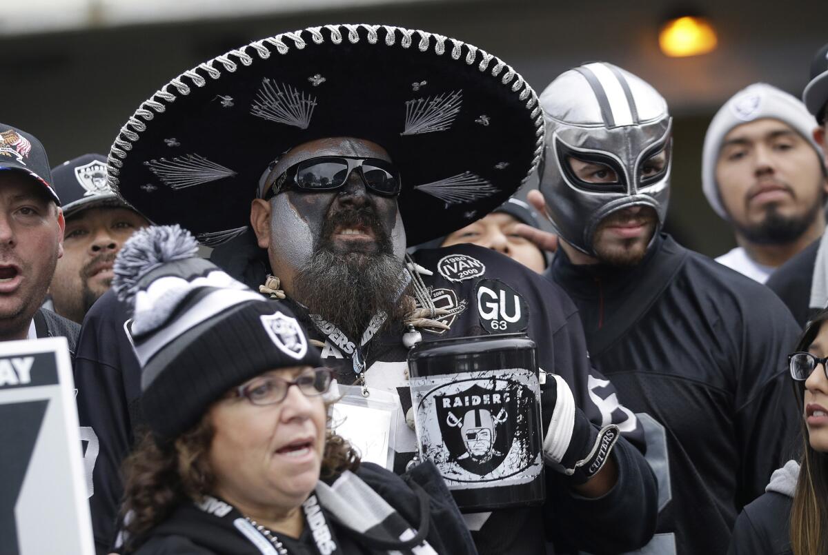 Oakland Raiders fans pose for photos while tailgating at O.co Coliseum before a game this season.