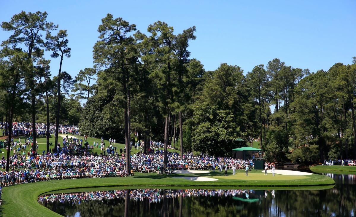 Patrons line the sixth green during the Masters par-three tournament at Augusta National Golf Club.