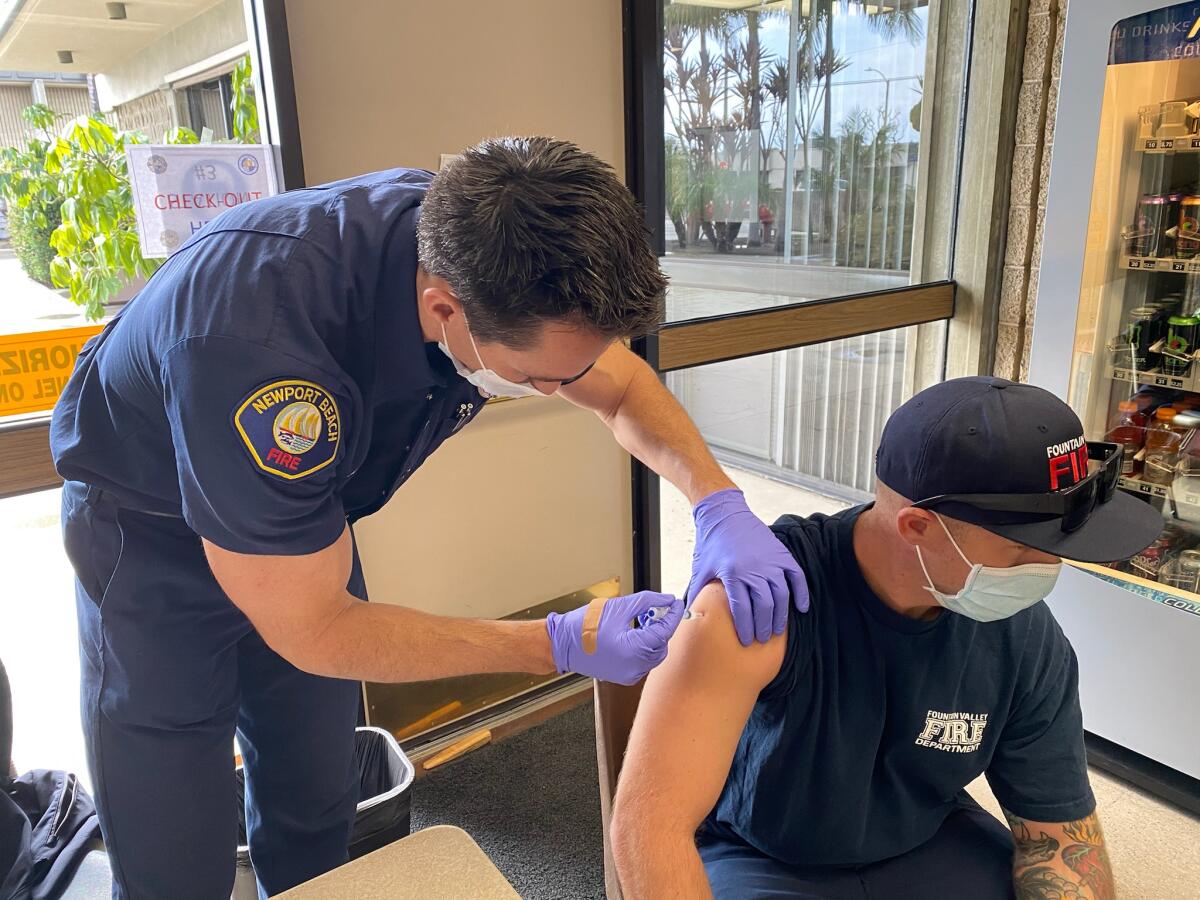 Newport Beach paramedic Adam Levins vaccinates a paramedic from Fountain Valley.