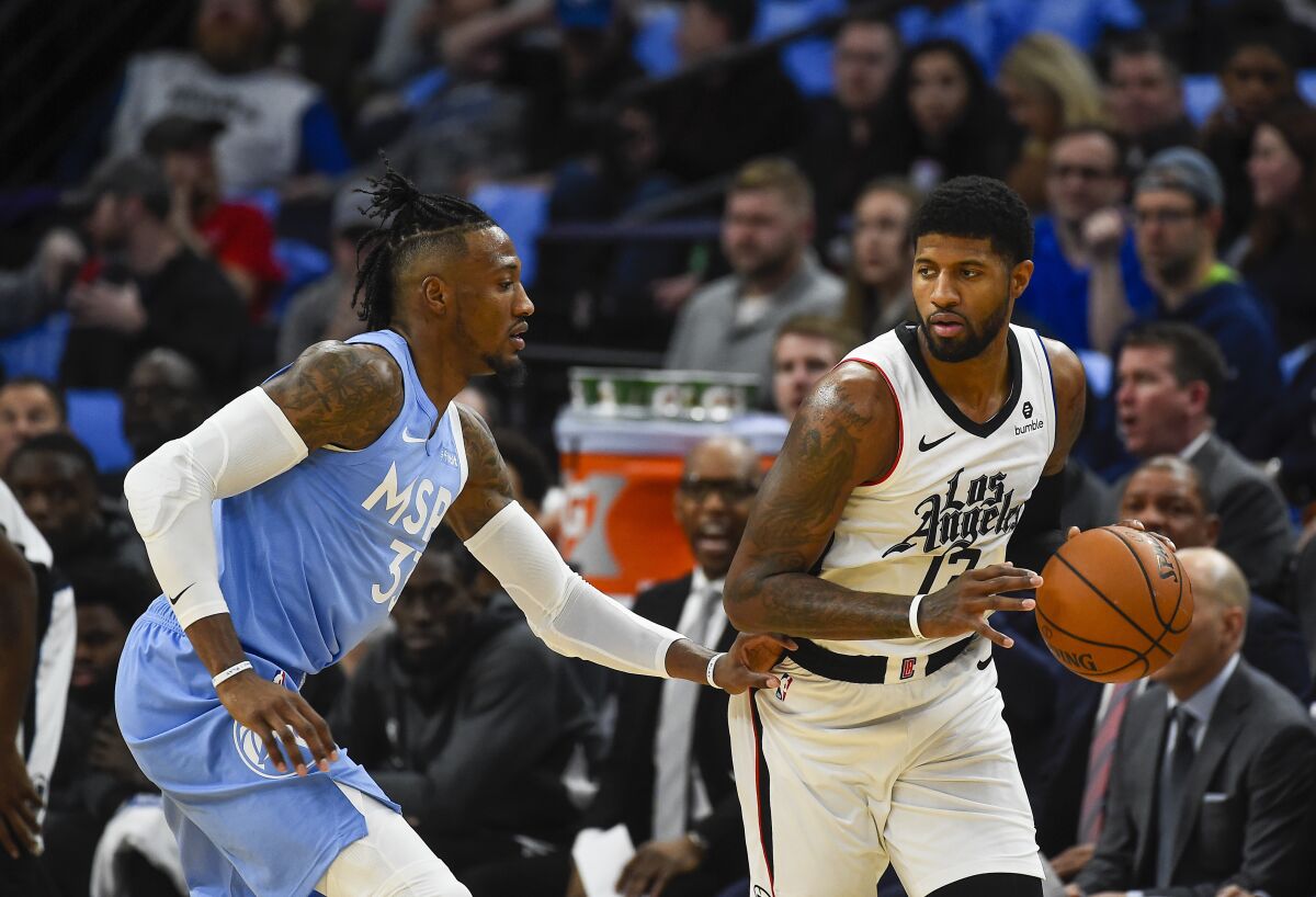 Clippers forward Paul George, right, tries to drive past Minnesota Timberwolves forward Robert Covington during the first half on Friday in Minneapolis.