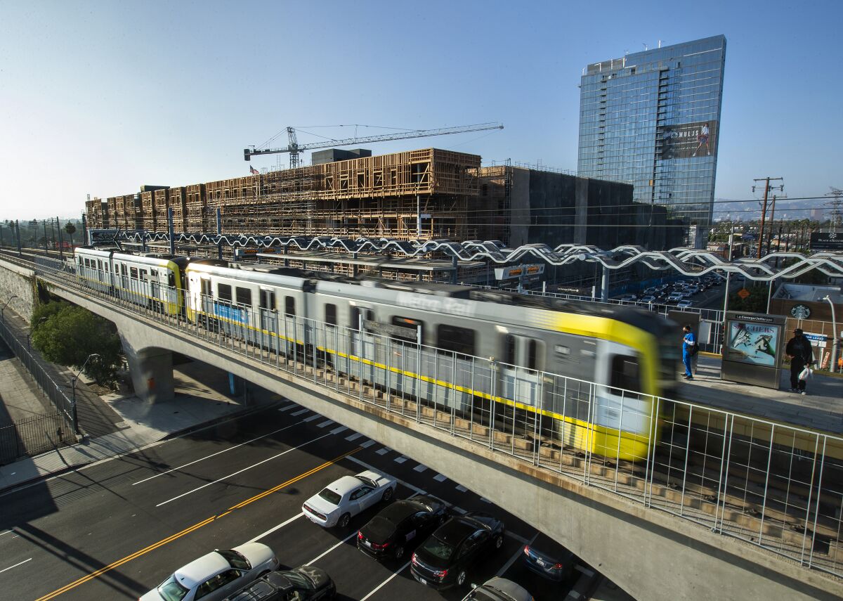 An Expo Line train at a station, with a construction project in the background