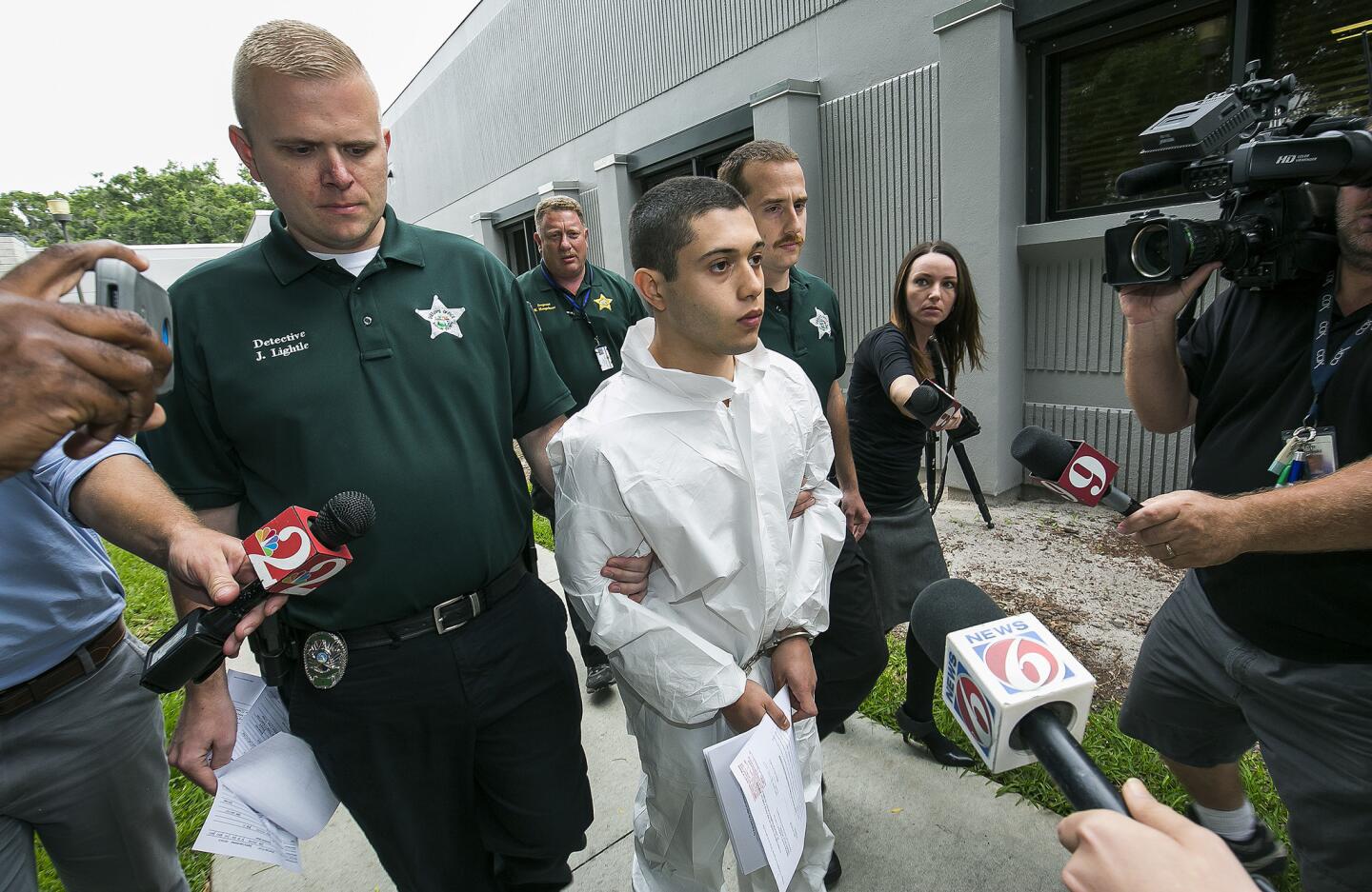 Marion County Sheriff's Detectives John Lightle, left, and Dan Pinder, right, escort a handcuffed and shackled Sky Bouche, 19, center, to a waiting patrol car, April 20, 2018, in Ocala, Fla. Bouche is the suspect in a shooting that occurred at Forest High School Friday morning.