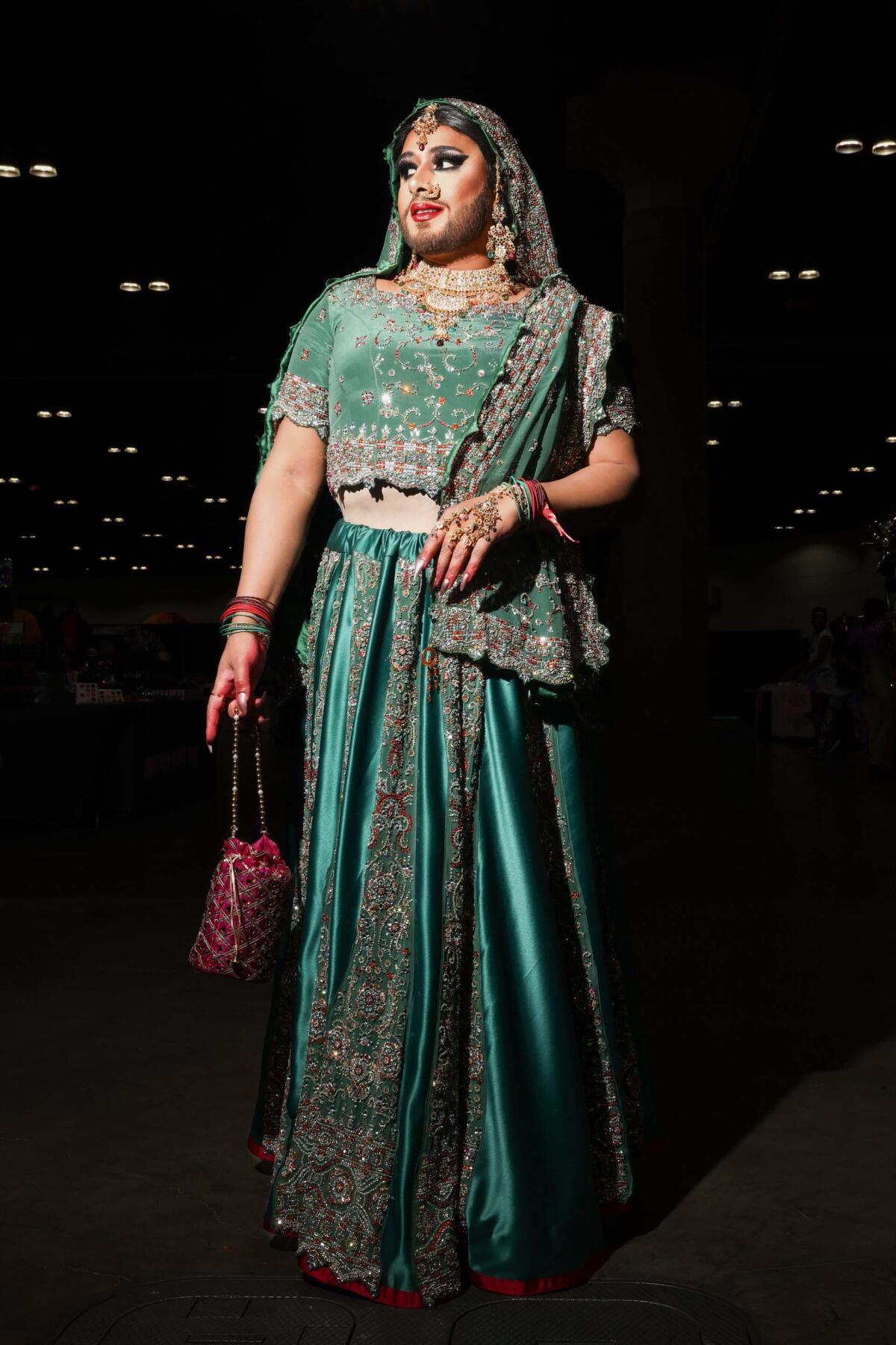 A person poses in an embellished emerald outfit. 