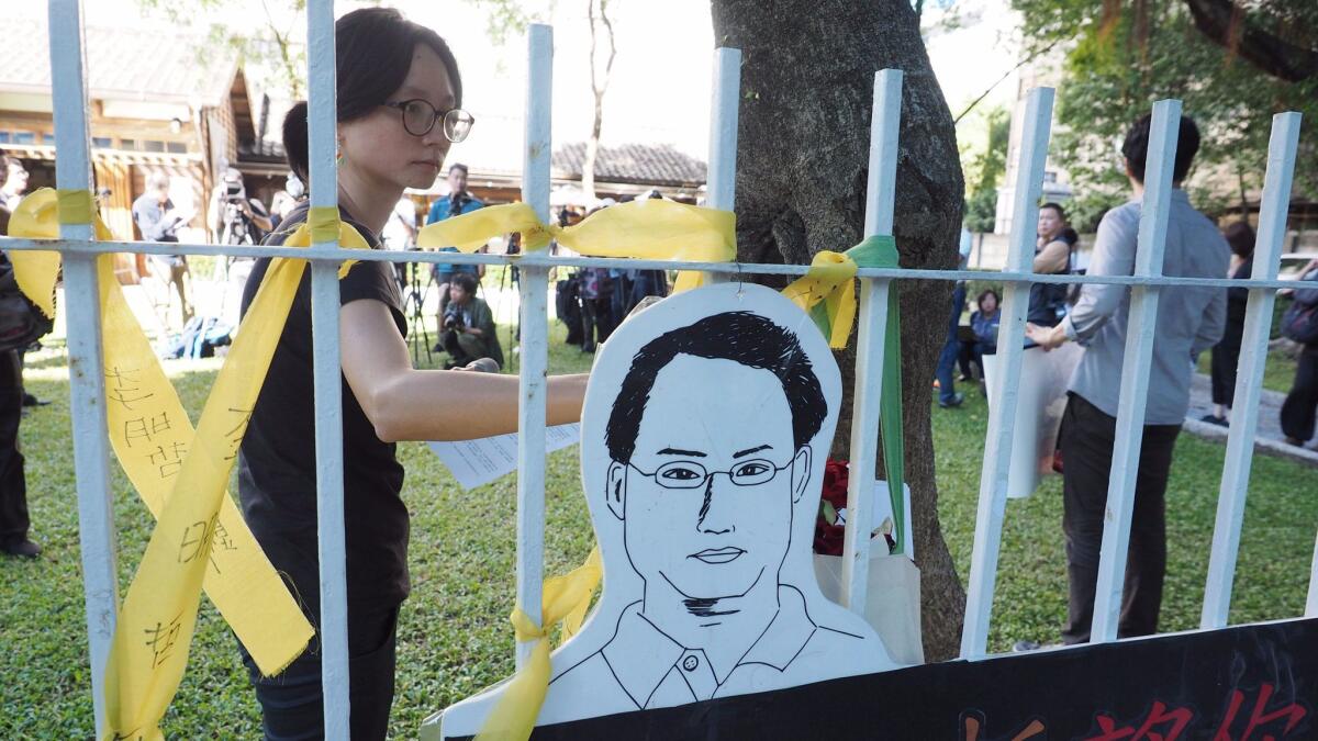 A woman ties a yellow ribbon for Taiwanese human rights activist Lee Ming-che in Taipei, Taiwan, on Nov. 28, 2017.