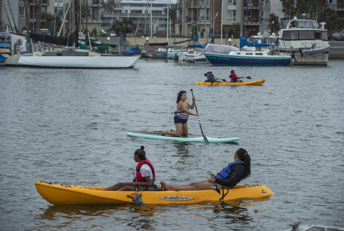 People paddle along in their kayaks and paddle board, center, during a visit to Marina Beach, also known as Mother’s Beach