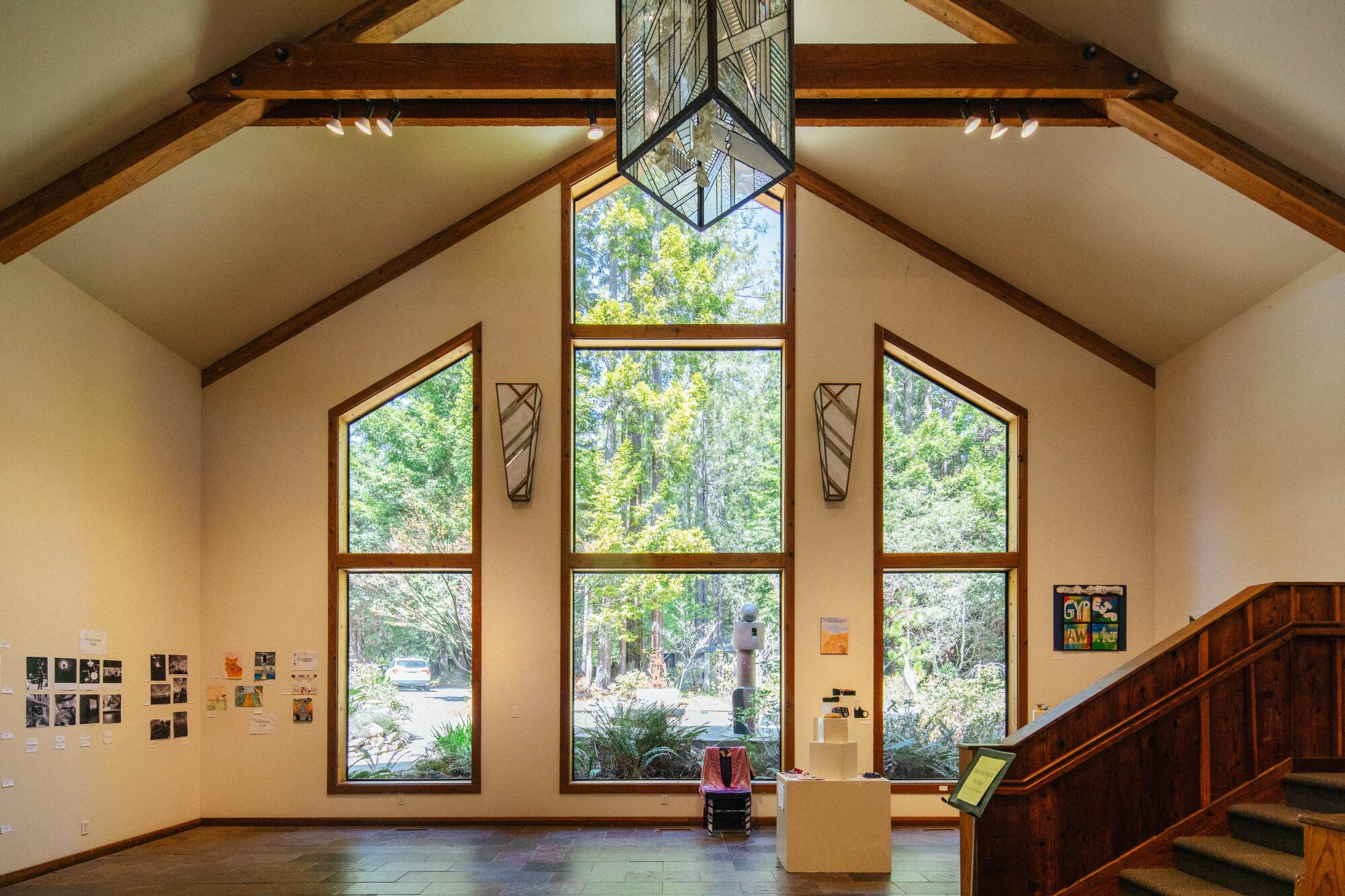 Inside Gualala Arts Center looking out through windows toward trees.