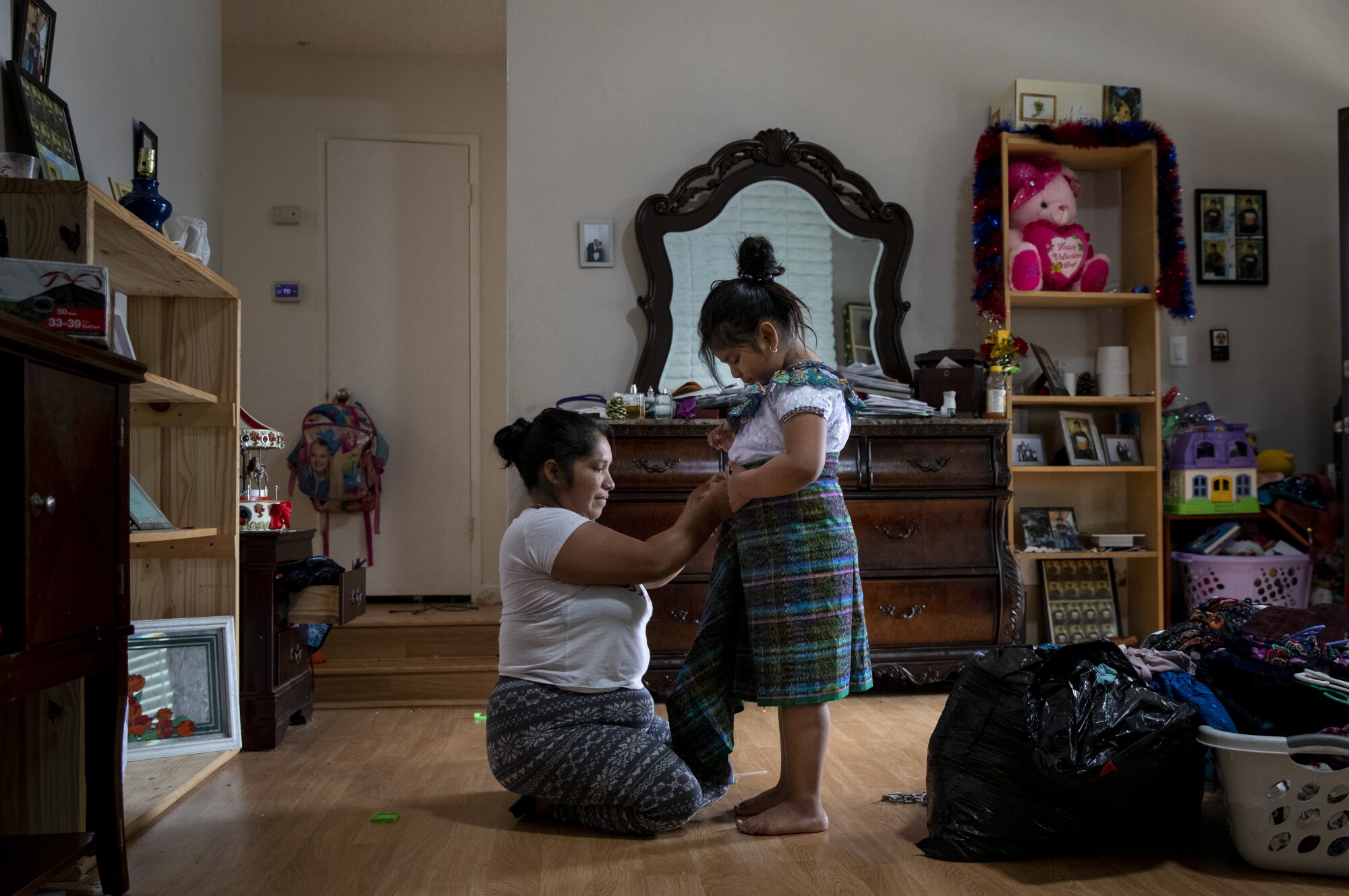 Maria Perez pauses from packing to dress up her daughter, Jennifer, 6, in clothes from Guatemala