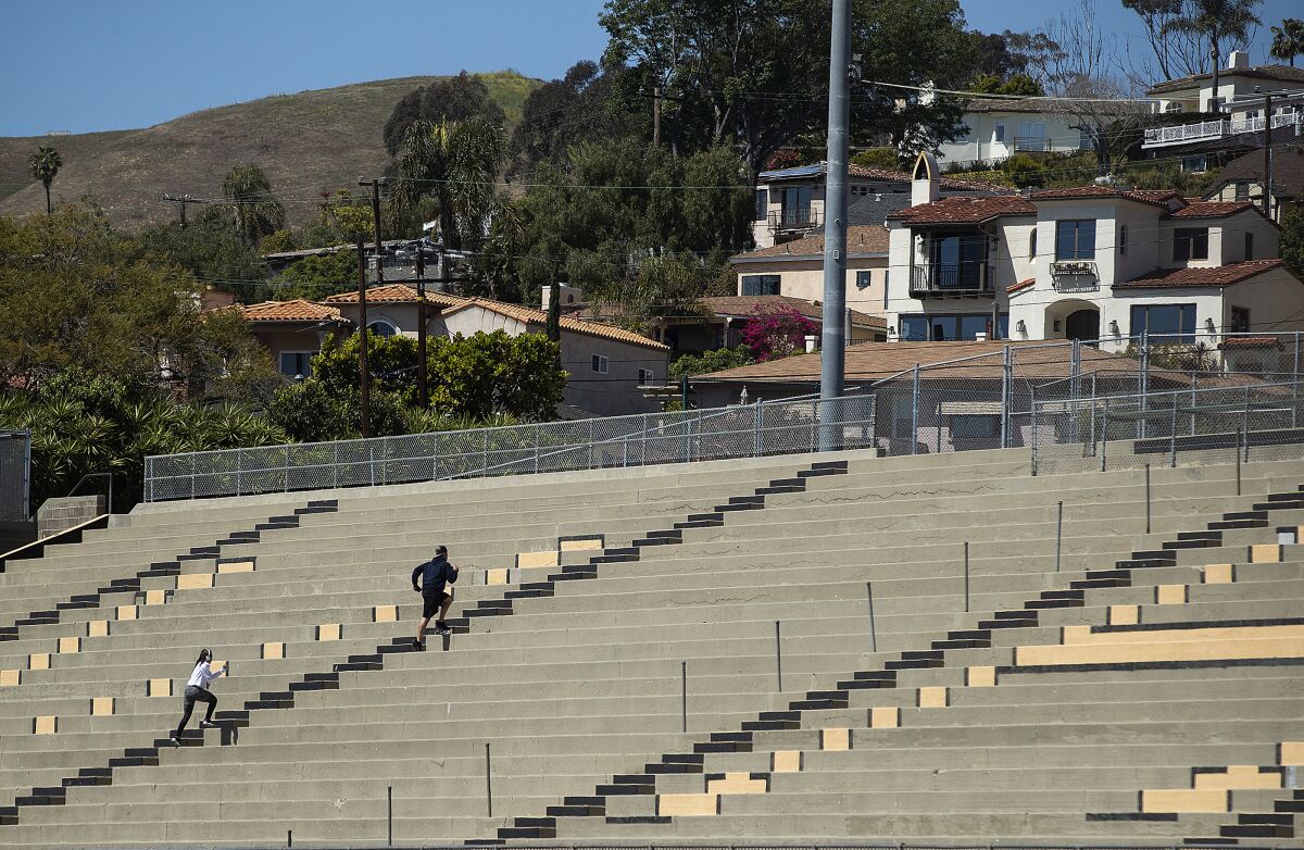 People run up the steps while working out at Larrabee Stadium on the Ventura High School campus. The stadium is closed as a result of the coronavirus outbreak but people are climbing over the fence to get inside.