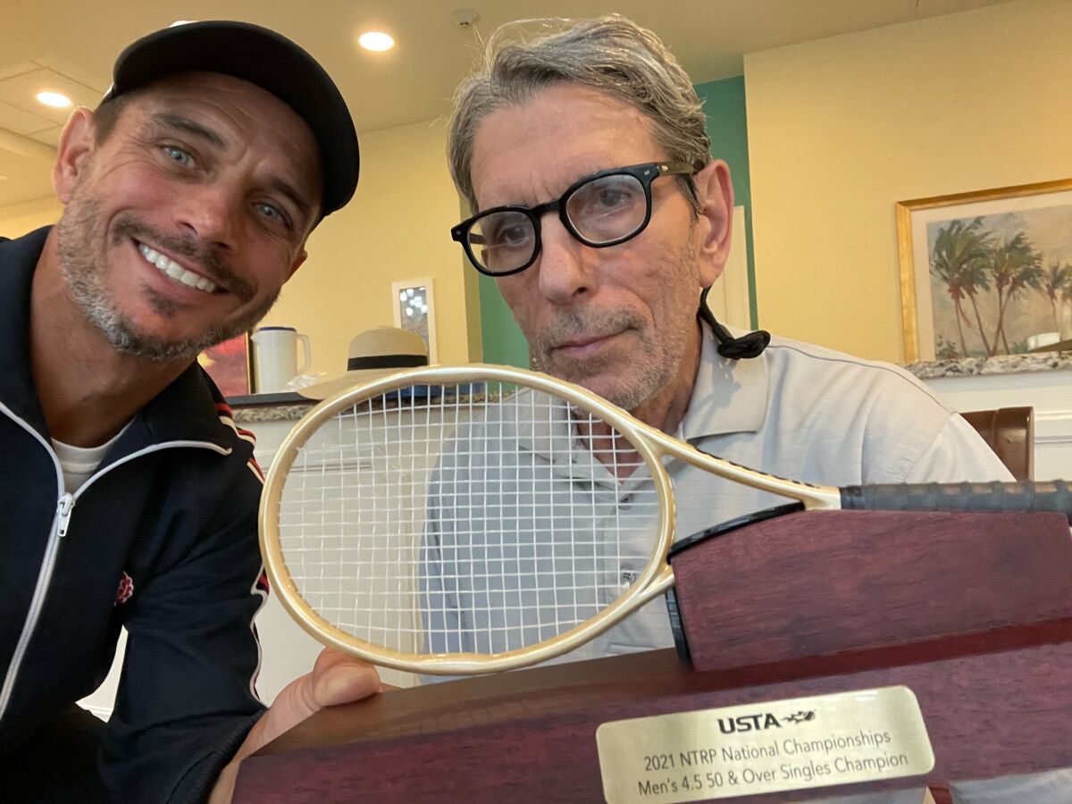 Rob Strasberg (left) shares his tennis trophy with his father, Ron, who taught him the game.