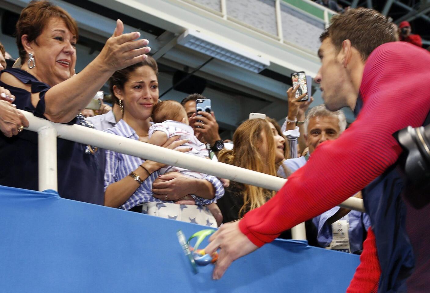 Michael Phelps of USA (R) goes to see his mother Deborah (L), his fiancee Nicole Johnson (C) and their son Boomer during the round of honour after the medal ceremony for the men's 200m Butterfly final race of the Rio 2016 Olympic Games Swimming events at Olympic Aquatics Stadium at the Olympic Park in Rio de Janeiro, Brazil.