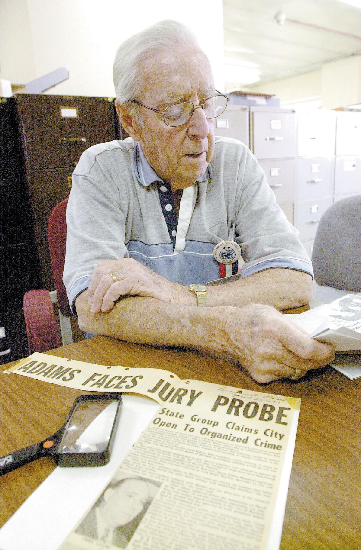 In this 2003 photo, retired Burbank Police Officer Harry Strickland looks over some news clippings from his career, as well as one involving Mickey Cohen and the Police Chief, Elmer Adams, who resigned amid allegations he was tied to Cohen and organized crime.