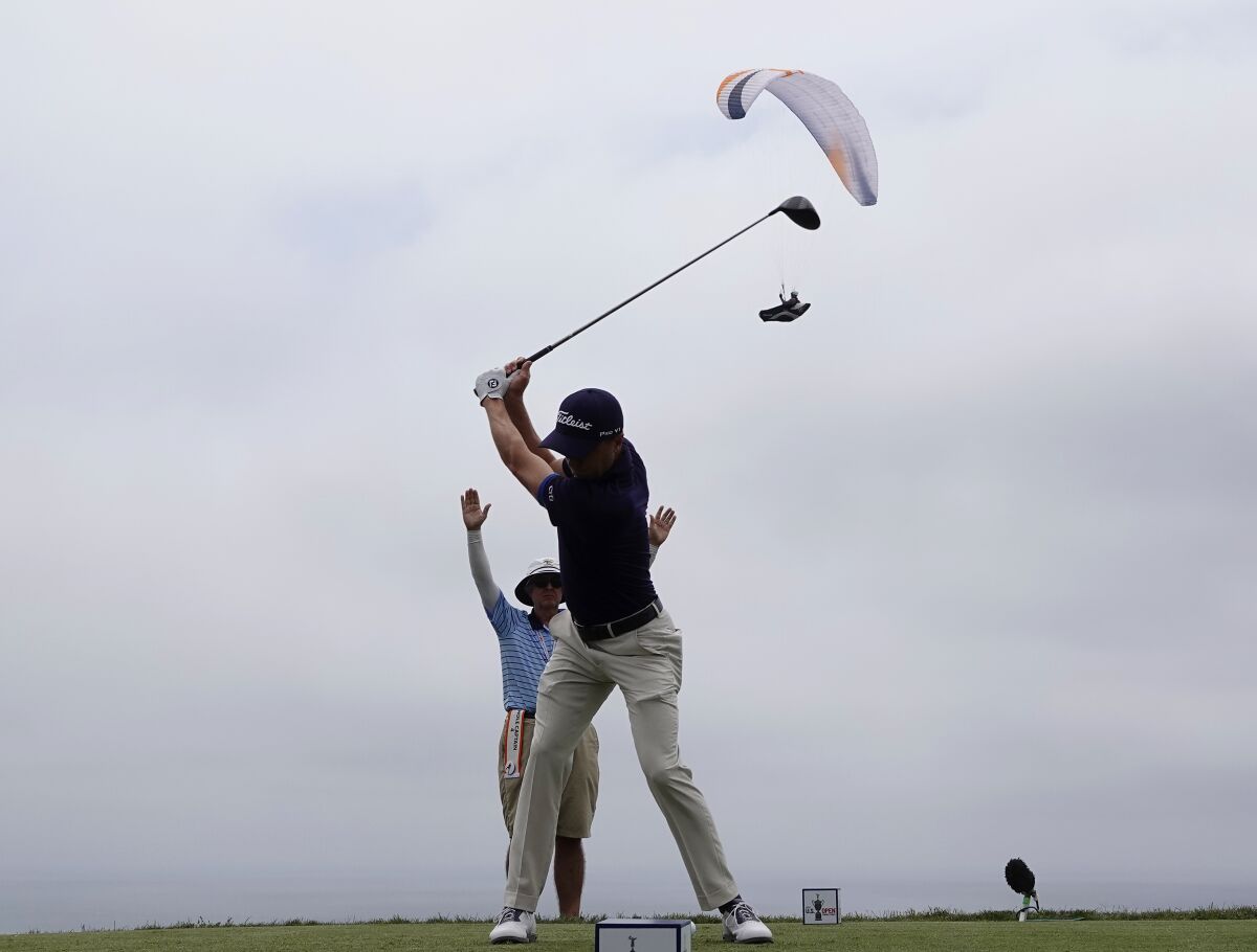 A paraglider flies near the fourth hole as Justin Thomas tees off during the second round.