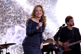 Adele smiles in a navy blue gown while performing onstage in Munich