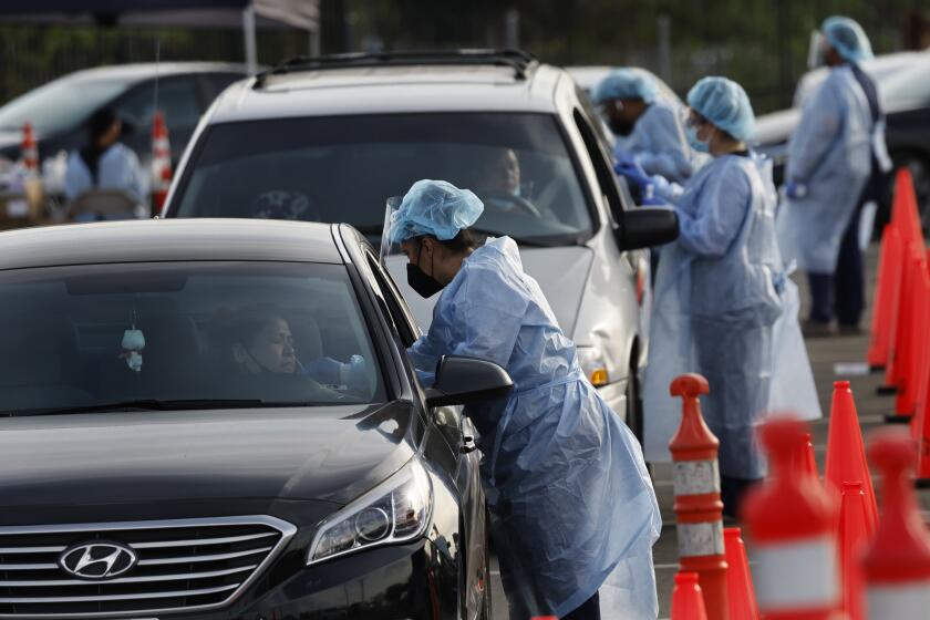 NORWALK, CA - JANUARY 12, 2022: Health care workers administer COVID-19 tests at the drive-thru mega testing site on the east side of the Norwalk/Santa Fe Springs Metrolink Station on January 12, 2022 in Norwalk, California.(Gina Ferazzi / Los Angeles Times)