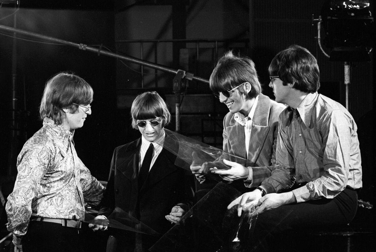 A black-and-white photo of four young men in the 1960s at a recording studio