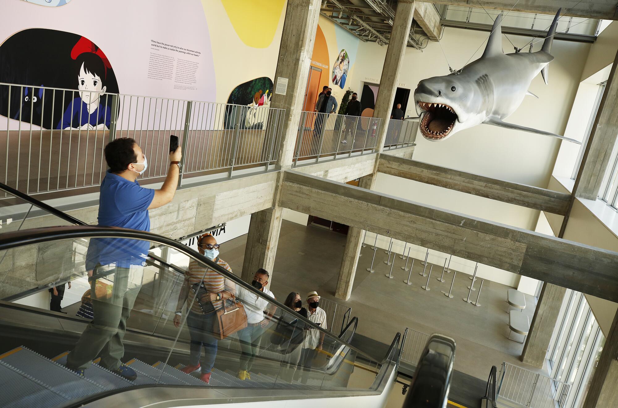 A man uses a cellphone to take a picture of Bruce the Shark from "Jaws."