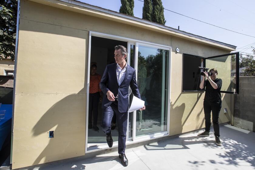 LOS ANGELES, CALIF. -- WEDNESDAY, OCTOBER 9, 2019: California governor Gavin Newsom steps out of Felicia Smith’s new garage conversion under construction after a tour in Los Angeles, Calif., on Oct. 9, 2019. The governor signed several housing bills in Smith’s backyard, where builders are converting her garage into a rental unit. (Brian van der Brug / Los Angeles Times)