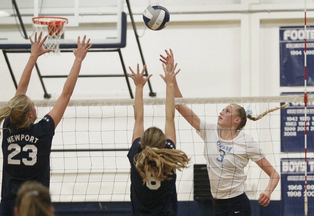Corona del Mar High's Hayley Hodson hits over Newport Harbor's Carolyn Bockrath, left, and Ellie Hagadorn during the Battle of the Bay girls' volleyball match on Saturday.