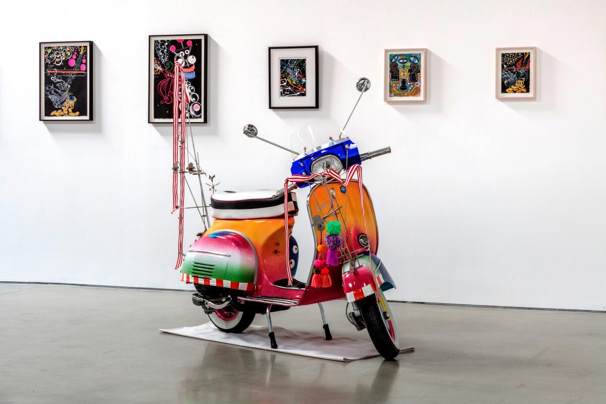 A colorful bike in a gallery with art hung behind it.