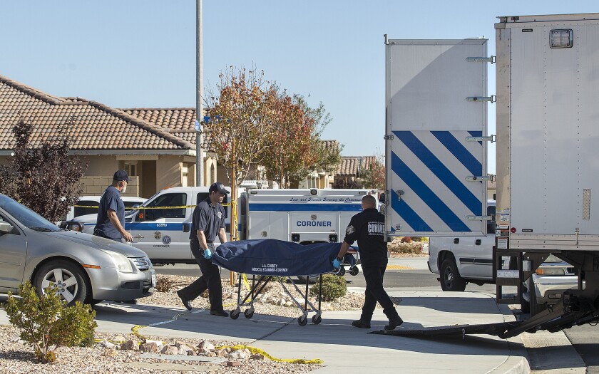 A body is loaded onto a coroner's truck in front of a home in the 3500 block of Garnet Lane in Lancaster.