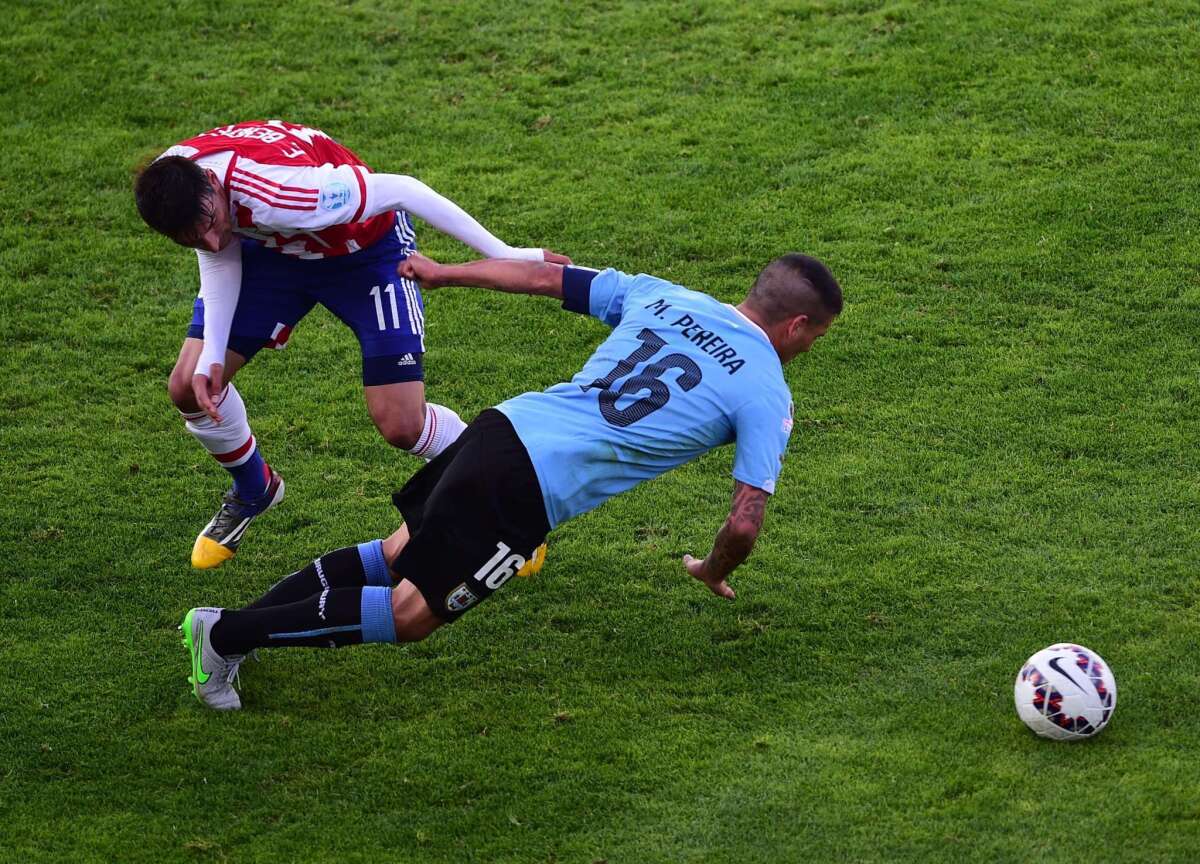 El uruguayo Maximiliano Pereira (der) es frenado por el paraguayo Edgar Benítez.