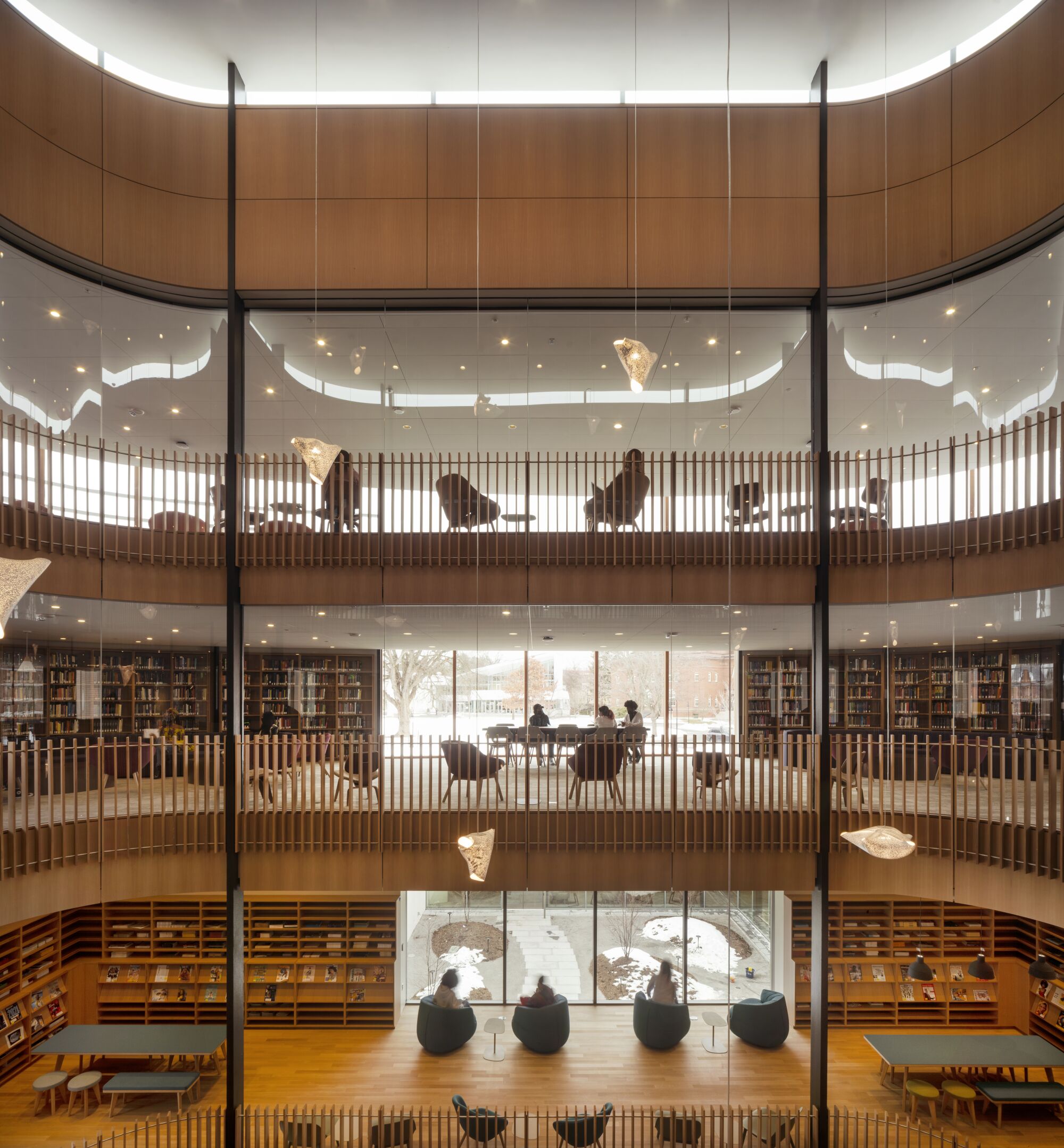 Three stories of wood-lined library rooms viewed from across an atrium.