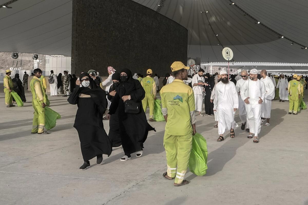Cleaners line up in front of pilgrims after they cast stones at a pillar in the symbolic stoning of the devil, the last rite of the annual Hajj pilgrimage, in Mina near the holly city of Mecca, Saudi Arabia, Wednesday, June 28, 2023. It takes tens of thousands of cleaners, security personnel, medics and others to make the annual Hajj pilgrimage possible for 1.8 million faithful from around the world. (AP Photo/Amr Nabil)