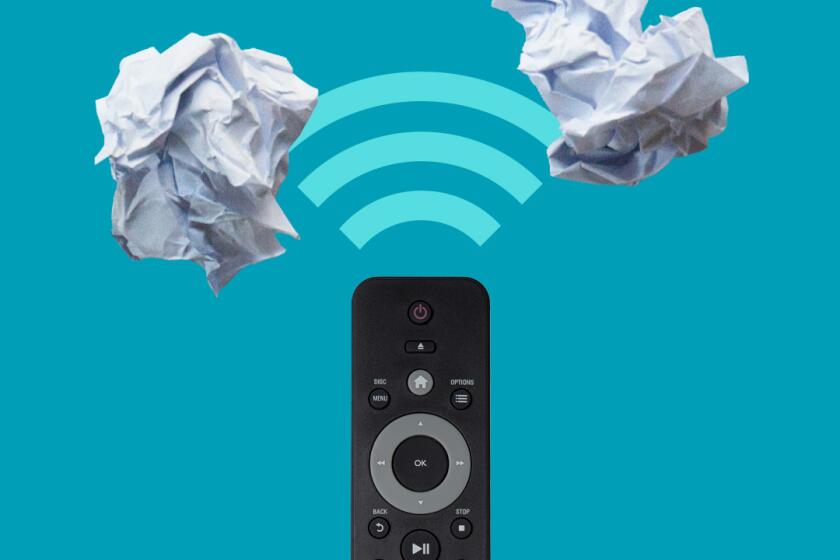 A remote control points toward two crumpled wads of paper.