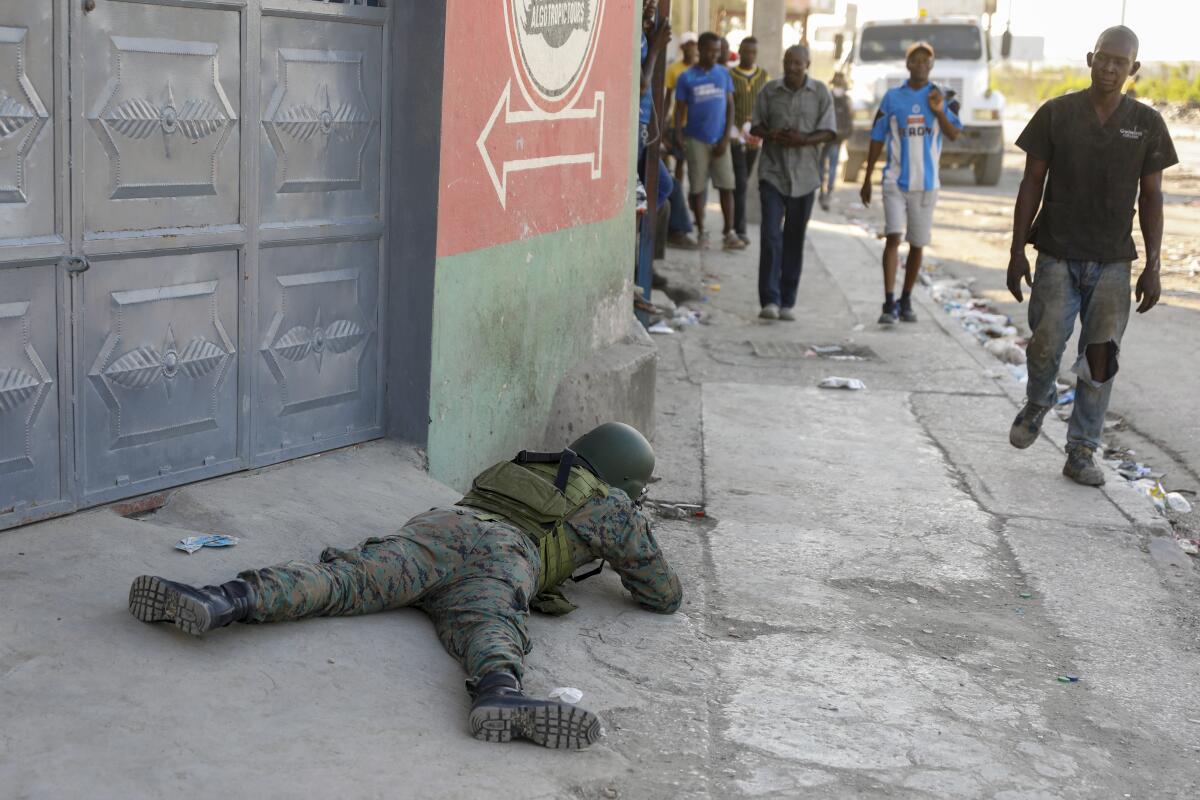 A helmeted soldier lies on a sidewalk as pedestrians in Port-au-Prince, Haiti