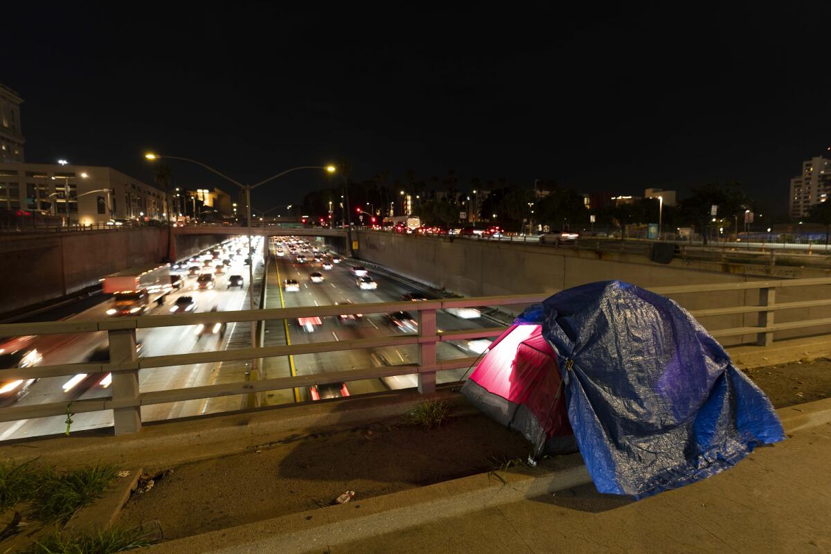 A tent on a bridge over a freeway at night 