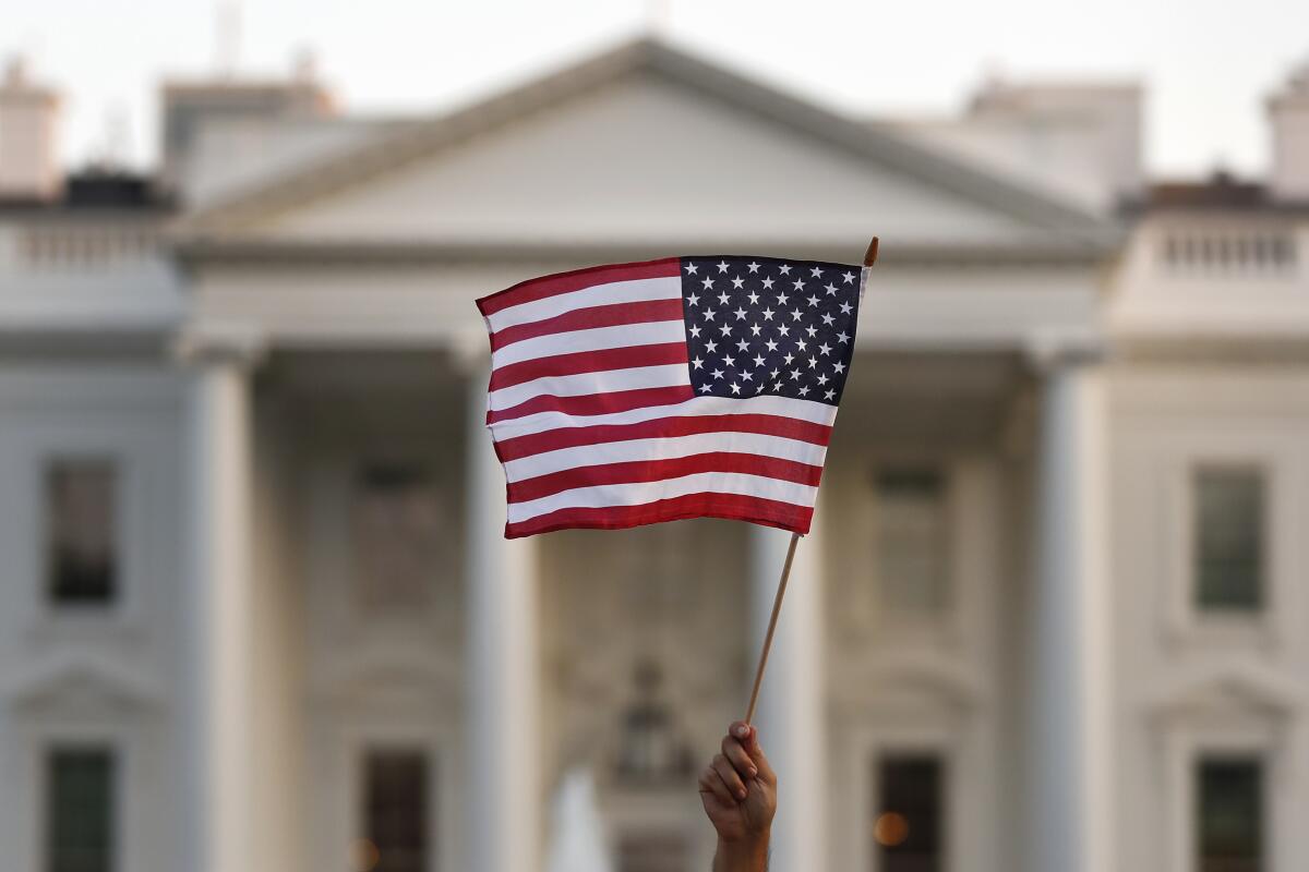 En esta imagen de septiembre de 2017, una persona ondea una bandera estadounidense a las afueras de la Casa Blanca, en Washington. (AP Foto/Carolyn Kaster)