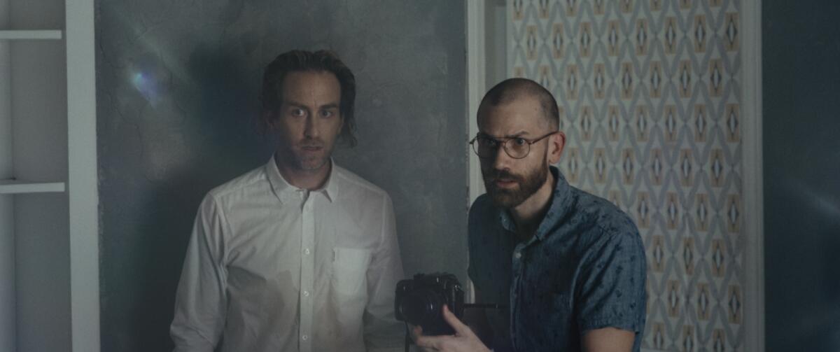 Two men nervously film something in a home in "Something in the Dirt."