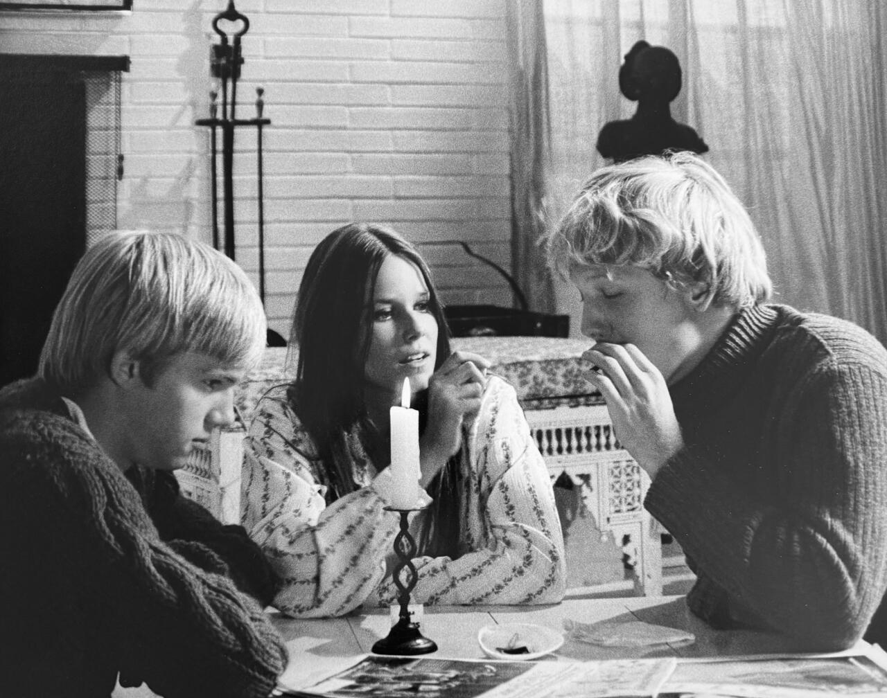 Three people lift a seagull on the beach.