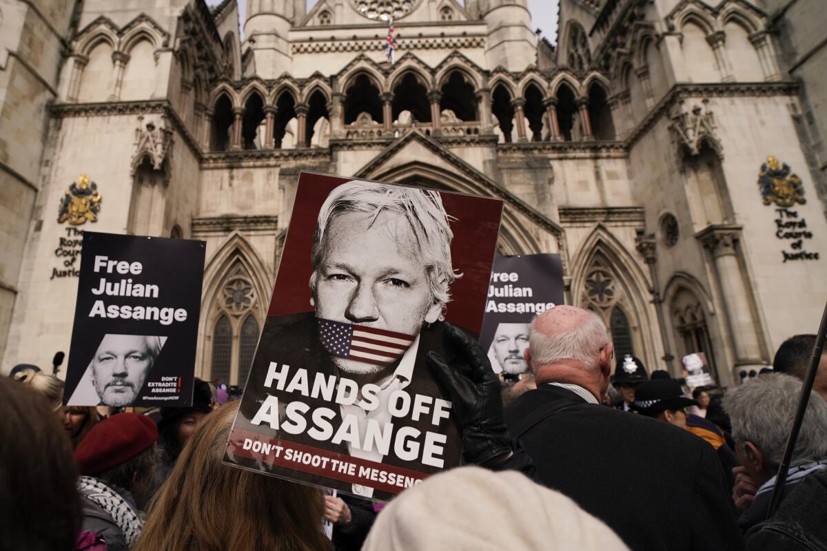 A  Julian Assange suporter holds a placard.