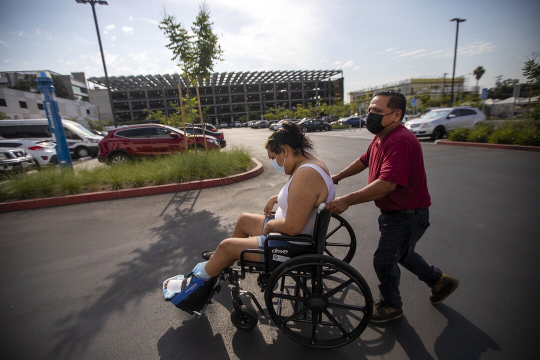 Jose Morales guides his 30-year-old stepdaughter Sandy Vazquez in a wheelchair
