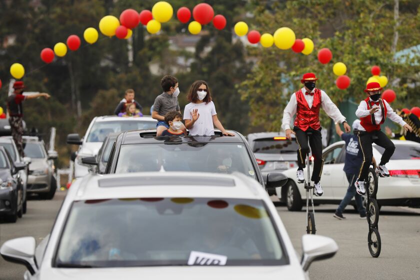 Families watch performers during a drive through circus to celebrate the Jewish festival of Lag B'Omer at the Chabad San Diego Headquarters Campus on May 12, 2020. Thousands of people attended the event that was complete with circus acts, live music, and festival floats.