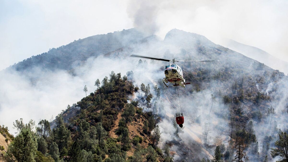 A helicopter gathers water from the Merced River to fight the Ferguson fire along steep terrain behind the Redbud Lodge near El Portal along Highway 140 in Mariposa County on Saturday, July 14, 2018.