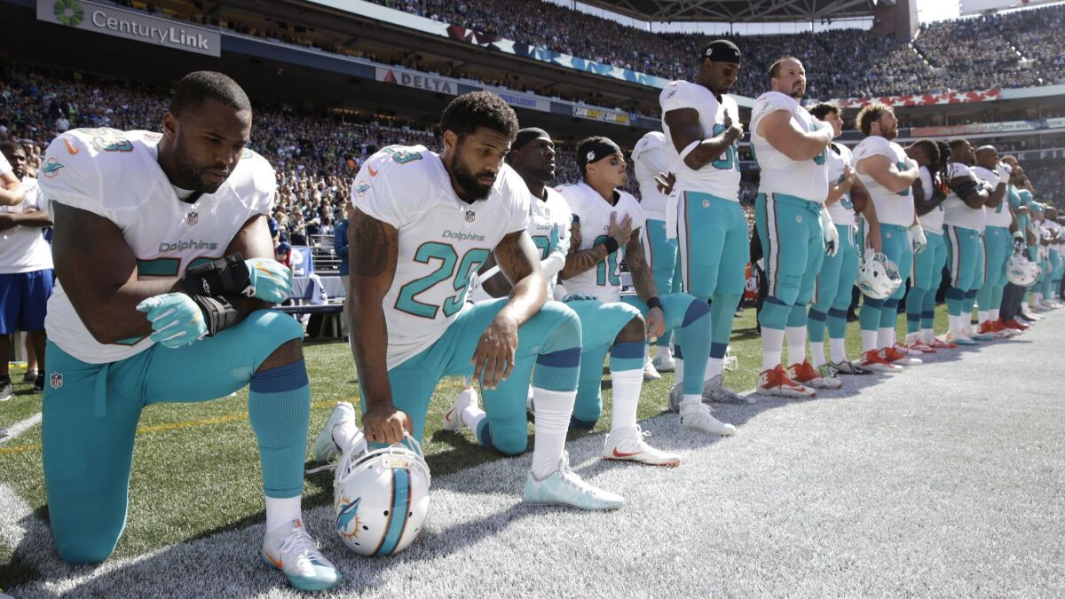 Miami Dolphins, from left, Jelani Jenkins, Arian Foster, Michael Thomas and Kenny Stills kneel during the national anthem before a game against the Seattle Seahawks on Sept. 11, 2017..