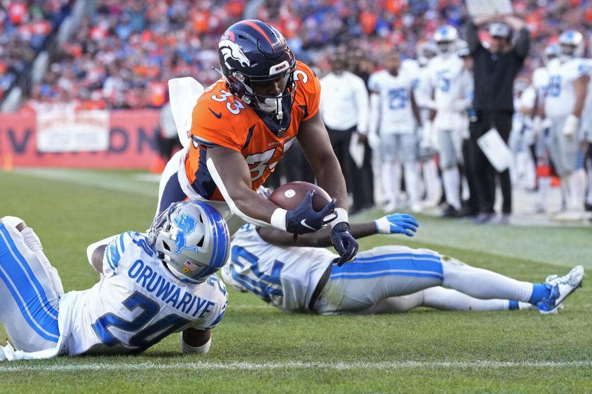 Denver Broncos running back Javonte Williams dives for a touchdown over Detroit Lions cornerback Amani Oruwariye on Sunday.