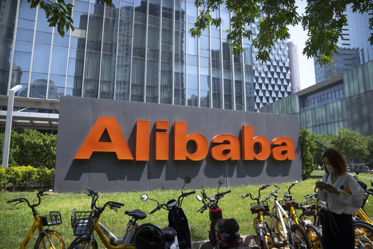 A large gray and orange Alibaba sign on a lawn outside a high-rise in Beijing