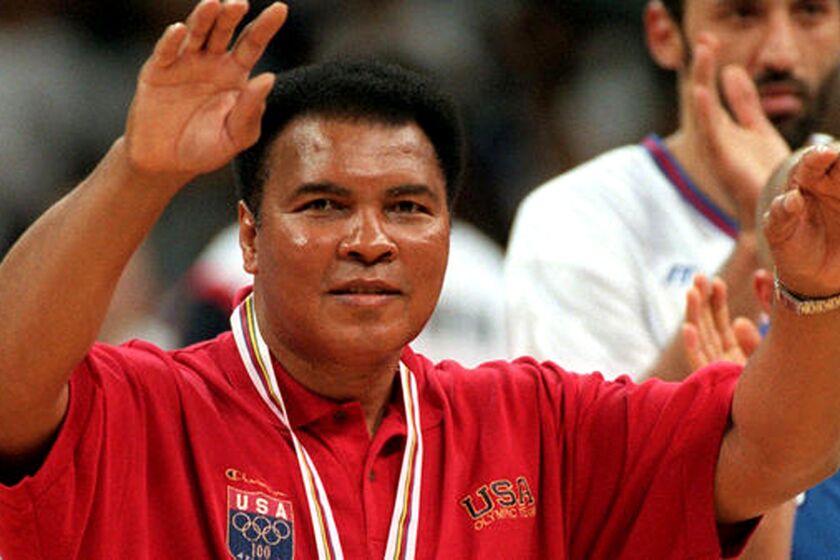 Muhammad Ali acknowledges the cheers of the crowd during halftime of the gold-medal basketball game between the United States and Yugoslavia at the Atlanta Olympic Games on Aug. 3, 1996.